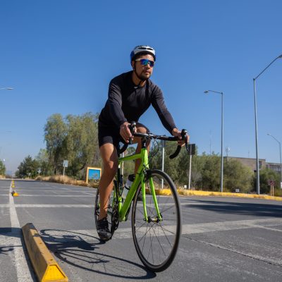 A low anglHispanic man in a sports suit riding a bicycle in a city