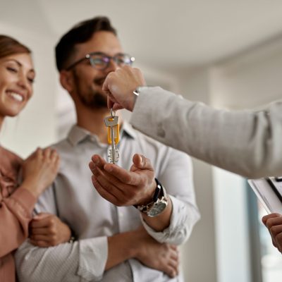 Close-up of a real estate agent giving to a couple keys of their new home.