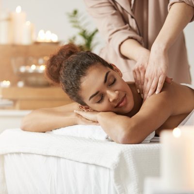 Tender beautiful african girl smiling enjoying massage with closed eyes in spa resort.
