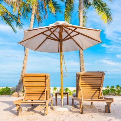 Umbrella and deck chair around outdoor swimming pool in hotel resort with sea ocean beach and coconut palm tree